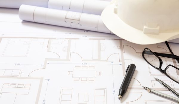 Project blueprints and engineer hardhat white color on drawings background. Housing project construction, architect site office concept.