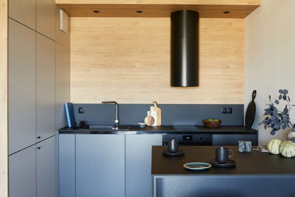 Stylish composition of modern small kitchen interior. Black furniture, workspace and dining space with black and light wooden kitchen accessories. Minimalistic masculine concept. Template.